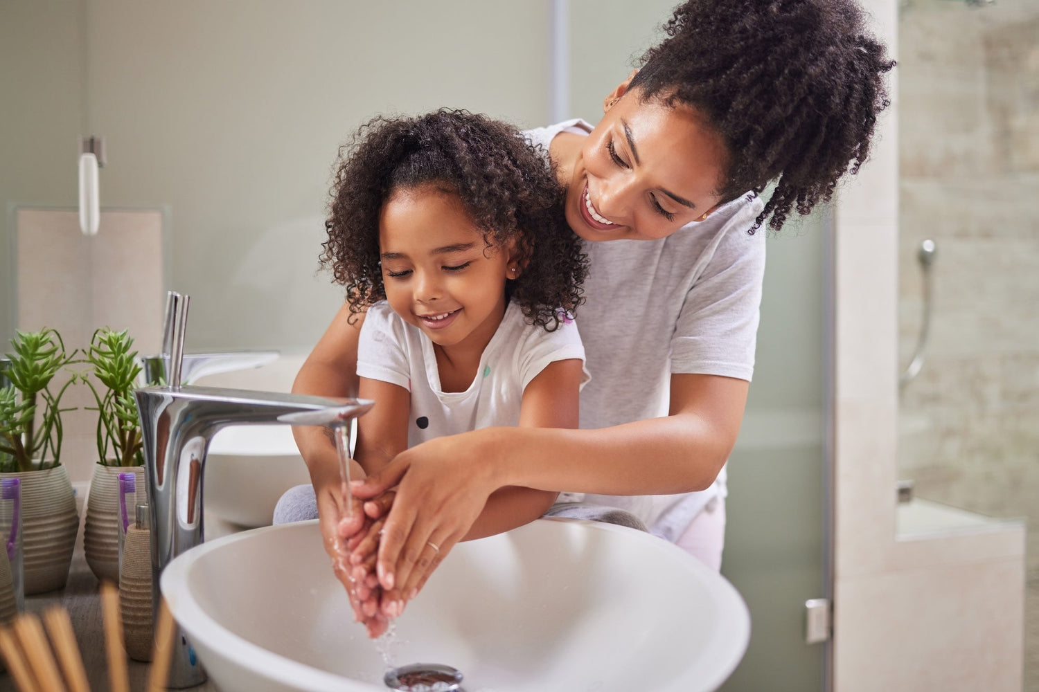 mom and daughter washing hands in a clean bathroom and sink area